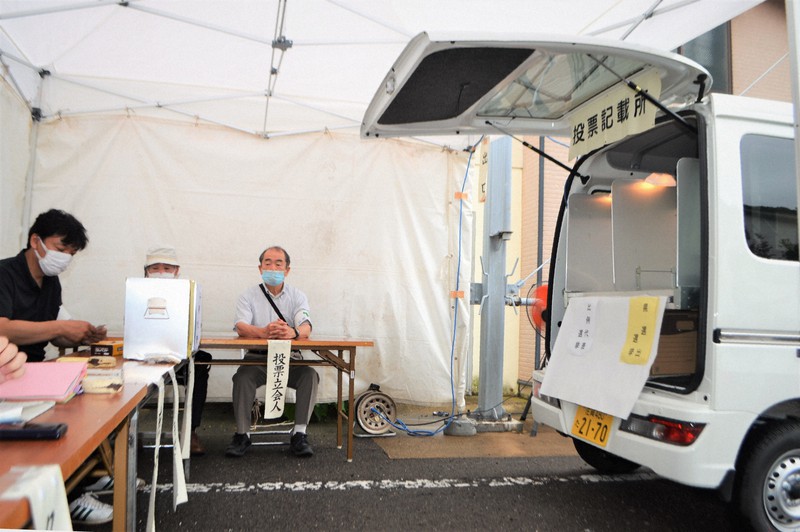 星賀高齢者センター駐車場にテントを設け、軽ワゴン車の荷室に記載台を置いた移動期日前投票所。机上の投票箱は、最初の投票者が中に何も入っていないことを確認してから荷室に移された=佐賀県唐津市で2022年7月5日午前8時45分、峰下喜之撮影