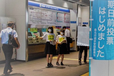 構内を行き交う人に啓発品を配って投票を呼び掛ける高校生＝桑名駅自由通路で（三重県桑名市提供）