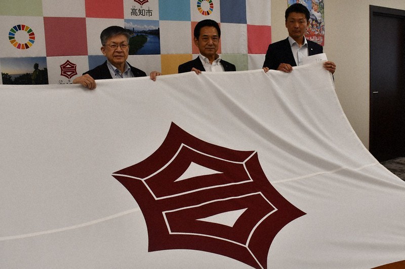岡崎誠也市長(左)から市旗を受け取った大田良継部長(中央)と小林健輔監督代行=高知市役所で、小宅洋介撮影
