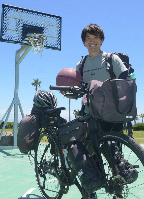 バスケットボールを抱え、自転車で日本一周をしている原匠さん=宮崎市阿波岐原町のサンビーチ一ツ葉で2022年7月1日午前11時45分、一宮俊介撮影