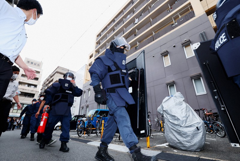 山上徹也容疑者宅のあるマンション(右奥)に爆発物などを警戒しながら家宅捜索に向かう捜査関係者ら=奈良市で2022年7月8日午後5時12分、滝川大貴撮影