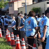 演説する岸田首相の背後をロープで囲い警備するボランティアと、周囲を警戒する警察官ら＝新潟市秋葉区で2022年7月9日、露木陽介撮影
