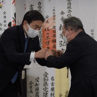 当選確実の一報にグータッチする藤川政人氏＝名古屋市中村区で10日午後8時10分