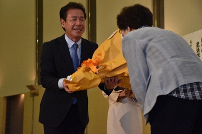 確実の報を受け、支援者から花束を受け取る小鑓隆史氏＝大津市におの浜4のびわ湖大津プリンスホテルで2022年7月10日午後8時32分、菅健吾撮影