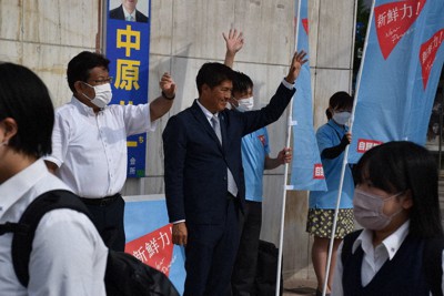 通学途中の高校生らに手を振る小林氏（中央）＝新潟市中央区で2022年7月11日、内田帆ノ佳撮影