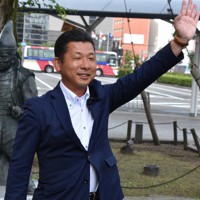 通勤、通学の人たちに手を振る若林洋平氏＝静岡市のJR静岡駅前で2022年7月11日、山田英之撮影