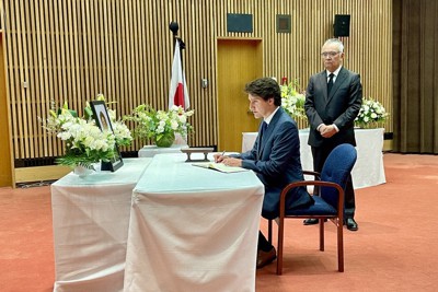 記帳するカナダのトルドー首相（中央）。右は山野内勘二・駐カナダ大使＝オタワの在カナダ日本大使館で2022年7月12日、在カナダ日本大使館提供