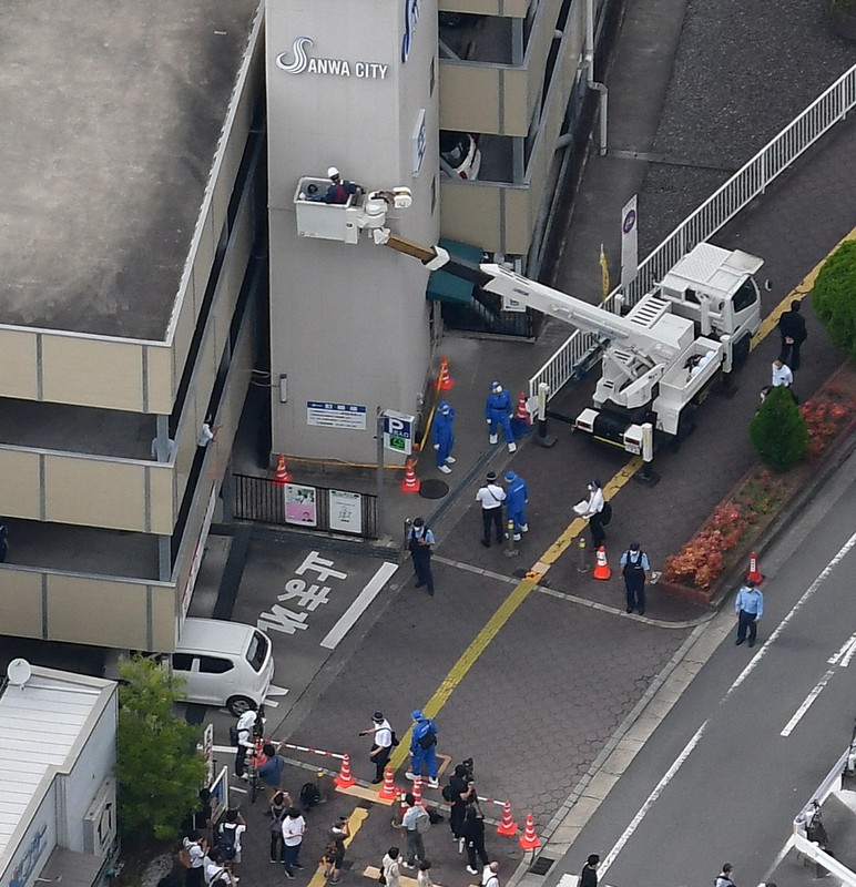 弾痕のようなものが見つかった立体駐車場の外壁を調べる捜査員ら=奈良市で2022年7月13日午後3時20分、本社ヘリから北村隆夫撮影