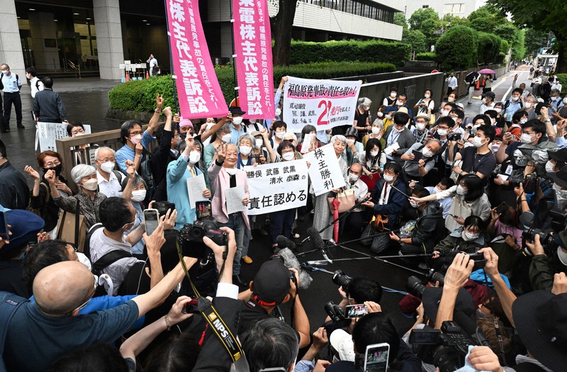 東京電力福島第1原発事故を巡る株主代表訴訟の判決後、「責任認める」などと書かれた紙を掲げ喜ぶ原告側関係者＝東京都千代田区の東京地裁前で2022年7月13日午後3時47分、西夏生撮影