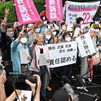 東京電力福島第1原発事故を巡る株主代表訴訟の判決後、「責任認める」などと書かれた紙を掲げ喜ぶ原告側関係者＝東京都千代田区の東京地裁前で2022年7月13日午後3時47分、西夏生撮影
