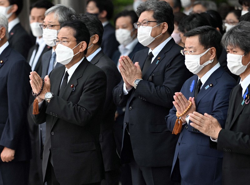 安倍晋三元首相のひつぎを乗せた車に向かい手を合わせる岸田文雄首相（左）。右から2人目は松野博一官房長官＝2022年7月12日、竹内幹撮影