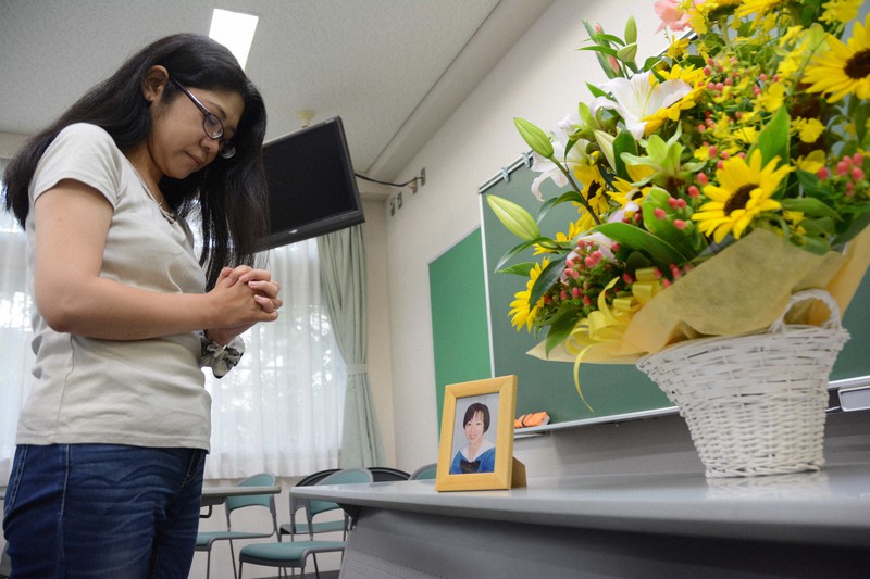 矢吹恵さんの写真を前に手を合わせる同級生の鷹野めぐみさん=東京都町田市の桜美林高校で2017年7月29日、深津誠撮影