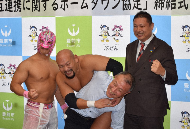 後藤市長(手前中央)にコブラツイストをかける桜島なおき選手。左は「めんたい☆キッド」選手、右は筑前理事長=福岡県豊前市で2022年7月25日、籔田尚之撮影