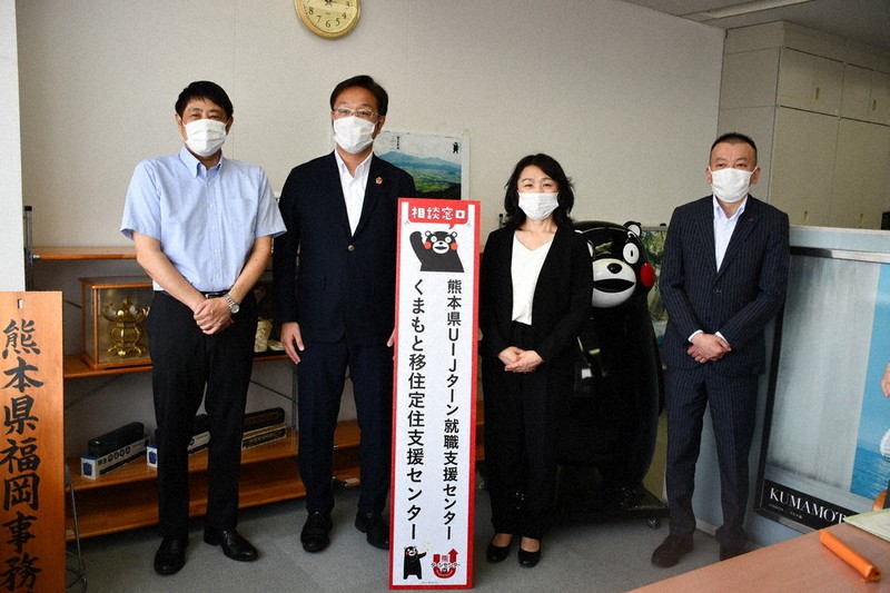 開所式で「くまもと移住定住支援センター」の看板を掲げる鳥井・熊本県福岡事務所長(左端)ら