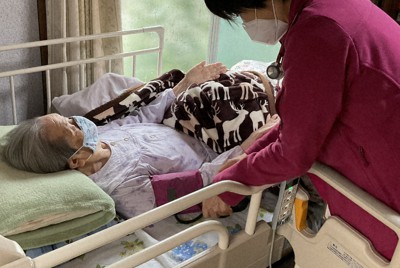 自宅療養する患者を診察する中村明澄医師（右）＝提供写真