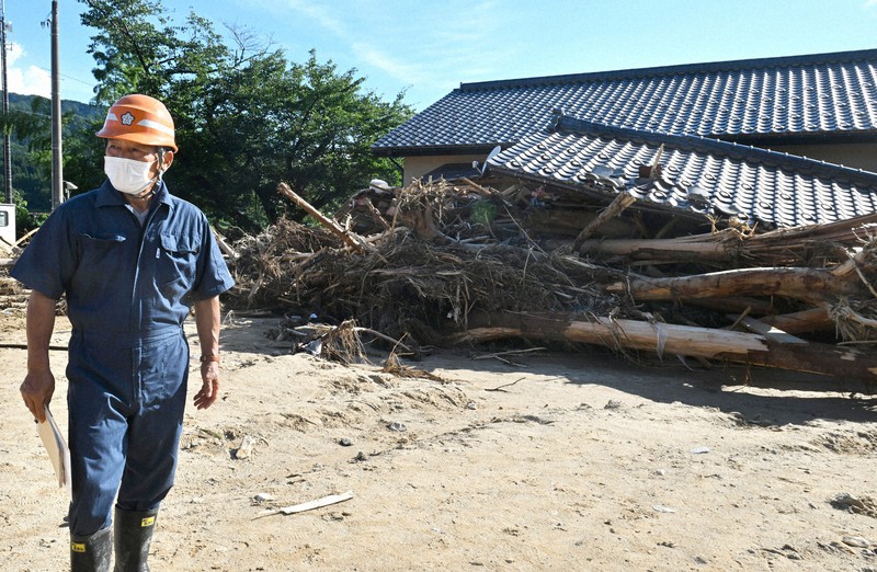 土砂の被害を受けた小岩内公会堂の前で周囲に目を配る小岩内地区の松本佐一区長=新潟県村上市で2022年8月5日午後4時2分、西夏生撮影