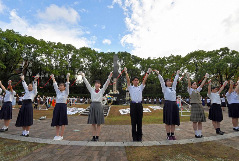 2021年8月9日に原爆落下中心地碑を囲むように人間の鎖を作り、平和を祈る高校生たち=長崎市で、平川義之撮影