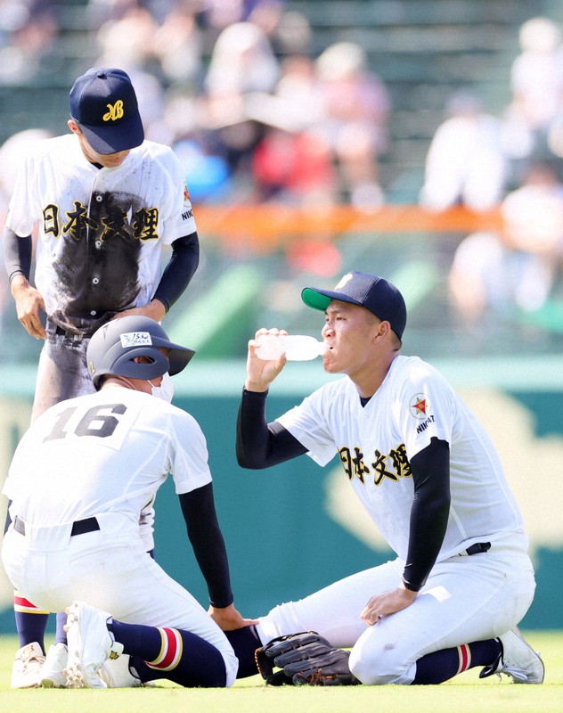 【海星-日本文理】六回途中で足がつり、水分補給をする日本文理の右翼手・玉木(右)=阪神甲子園球場で2022年8月8日、吉田航太撮影