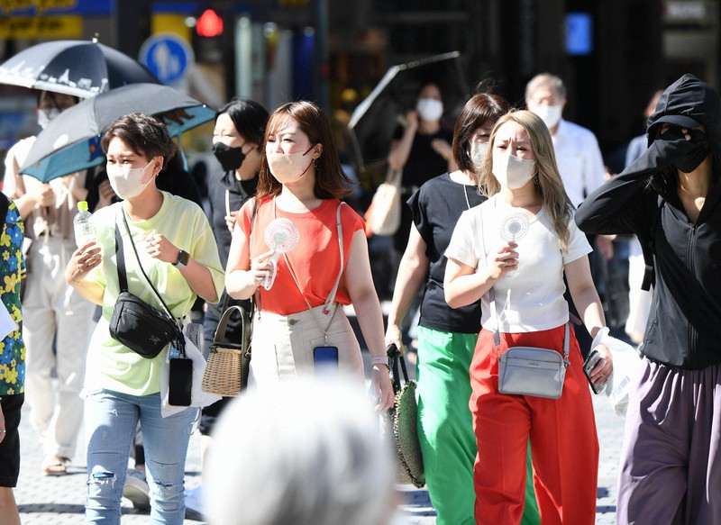 強い日差しの中、飲み物や小型扇風機を手に持って歩く人の姿が多く見られた=大阪市中央区で2022年6月29日午後3時24分、北村隆夫撮影