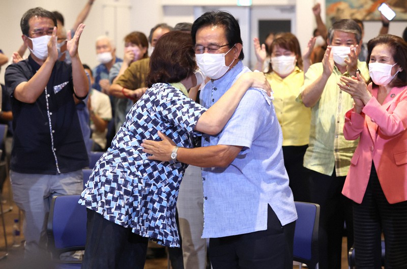 参院選沖縄選挙区で再選が確実となり、妻と抱き合う「オール沖縄」勢力の現職、伊波洋一氏(中央)=那覇市で2022年7月11日午前0時、喜屋武真之介撮影