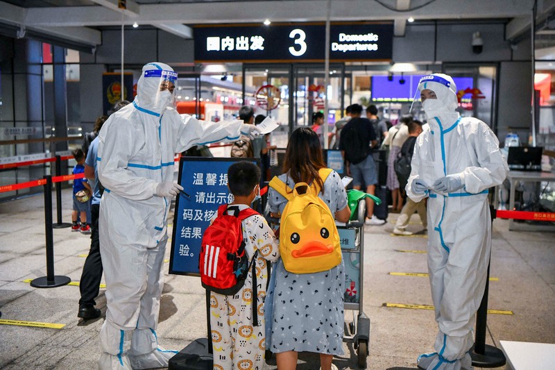 空港の出発ロビー入り口で、新型コロナウイルス関連の確認項目について案内を受ける乗客ら=中国南部・海南省海口で11日、CNSフォト・ロイター
