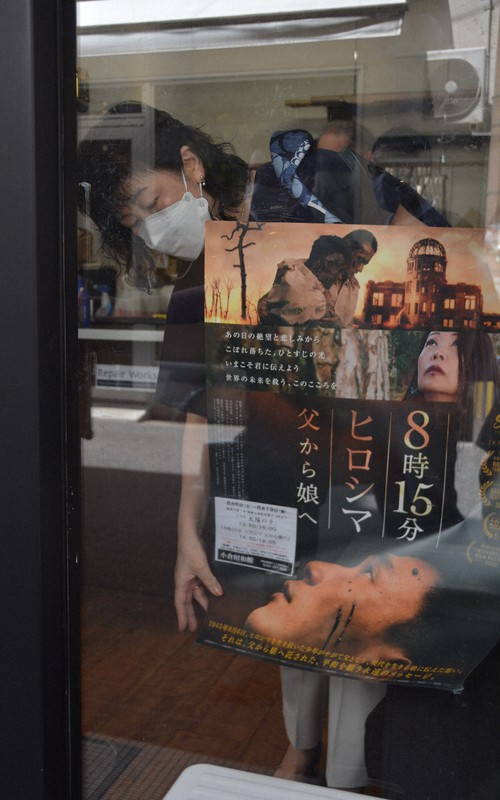 店の協力を得て、上映していた映画のポスターをはがす樋口さん=北九州市小倉北区で2022年8月14日午前11時50分、野間口陽撮影