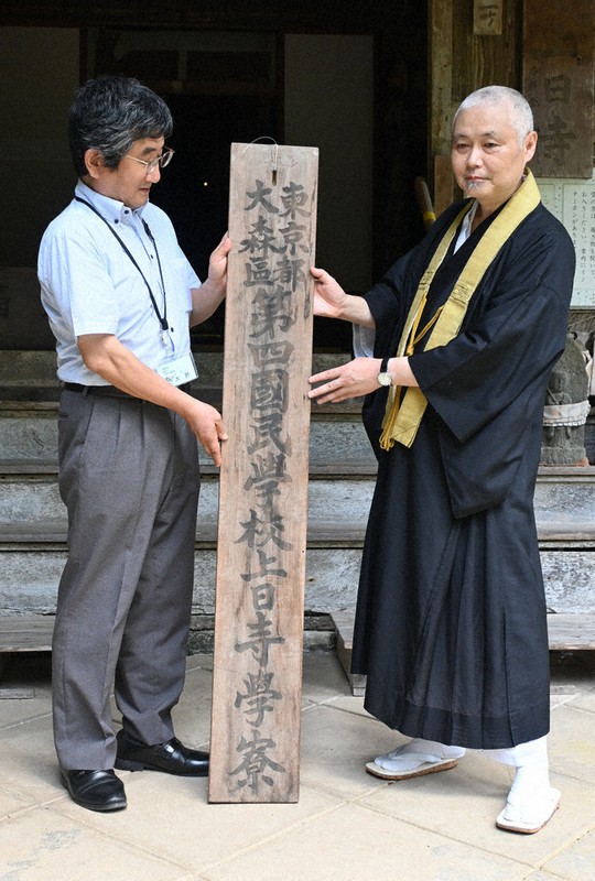 学童疎開の記憶を今に伝える看板を寄贈した柳原龍成住職(右)=富山県氷見市朝日本町の上日寺で、青山郁子撮影