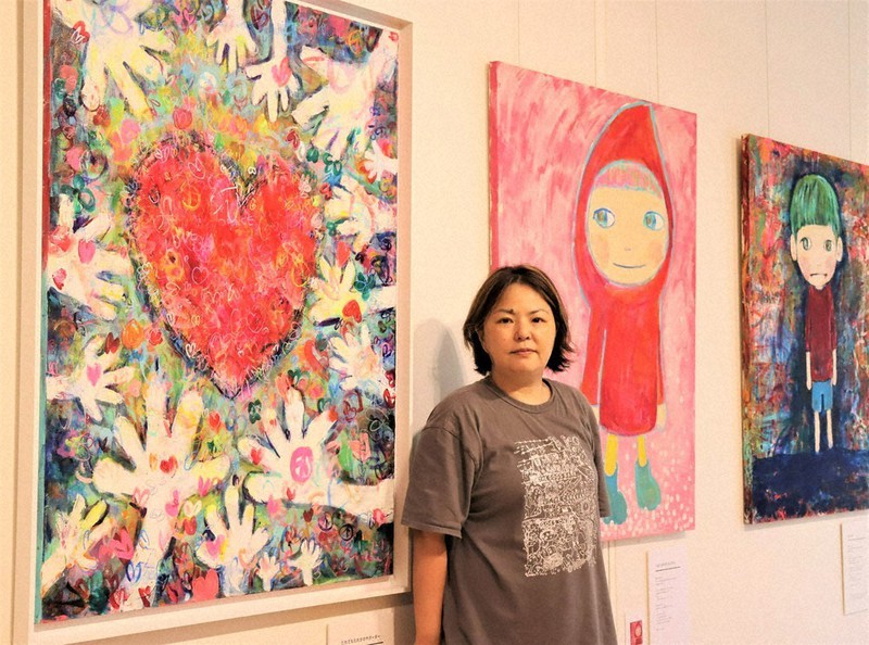 子どもたちの世界などを描いた作品の前に立つ細尾ちあきさん=さいたま市大宮区吉敷町1で、2022年8月17日、山崎恵利花撮影