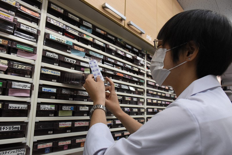 薬局でカロナールを手に取る薬剤師=2022年8月、秋丸生帆撮影