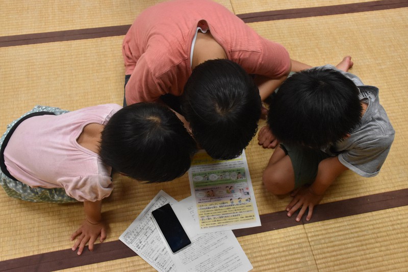 夏休み前に小学校から配られたネット・ゲームの利用時間についてのプリントを眺める子どもたち=高松市香南町で2022年8月25日午後8時24分、西本紗保美撮影