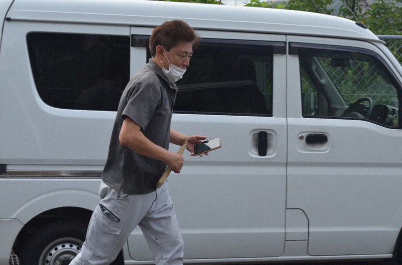 スマートフォンと荷物を手に配達先へ走る配達員の大滝さん