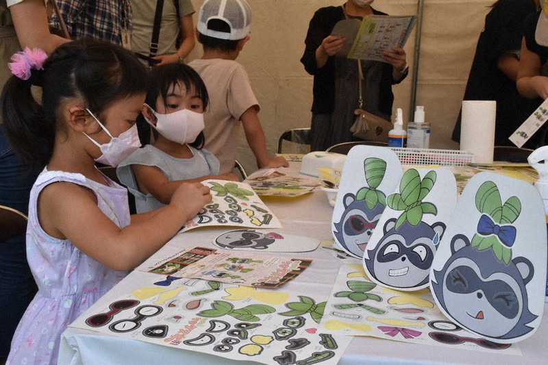 成安造形大の学生がデザインしたシールを貼りながら、思い思いのタヌキのお面を作る子供たち=大津市浜町の湖岸なぎさ公園で2022年9月10日午後1時49分、菅健吾撮影