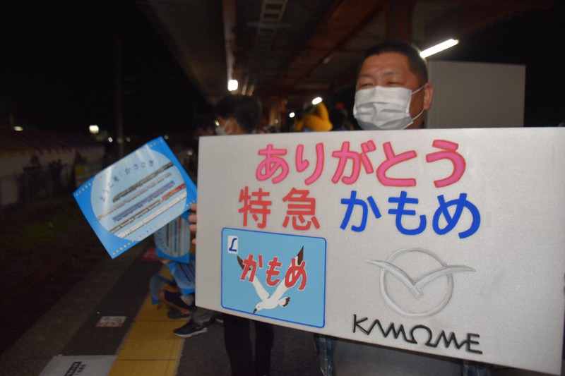 手作りのボードを持って特急「かもめ」の上り最終列車を待つ米倉禎敦さん=佐賀県鹿島市で2022年9月22日午後10時46分、山口響撮影