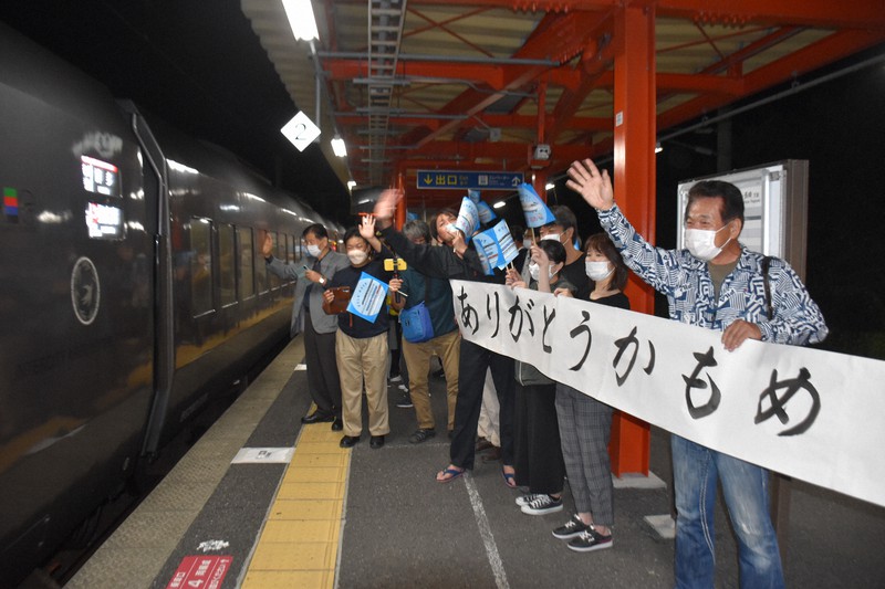 「ありがとうかもめ」と書かれた横断幕や手振り旗を持って、特急「かもめ」上り最終列車を見送る多くの人たち=佐賀県鹿島市で2022年9月22日午後10時49分、山口響撮影