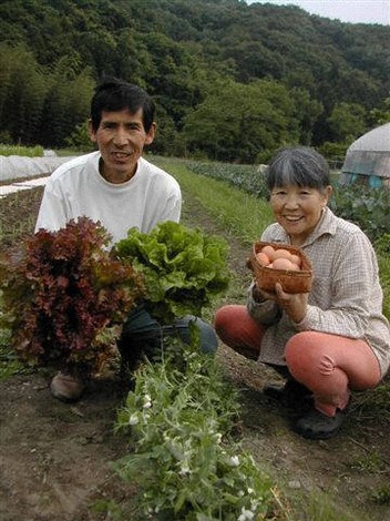有機農業で育てた収穫物を手にする金子美登さん(左)と妻の友子さん=小川町の霜里農場で2011年5月、明珍美紀撮影