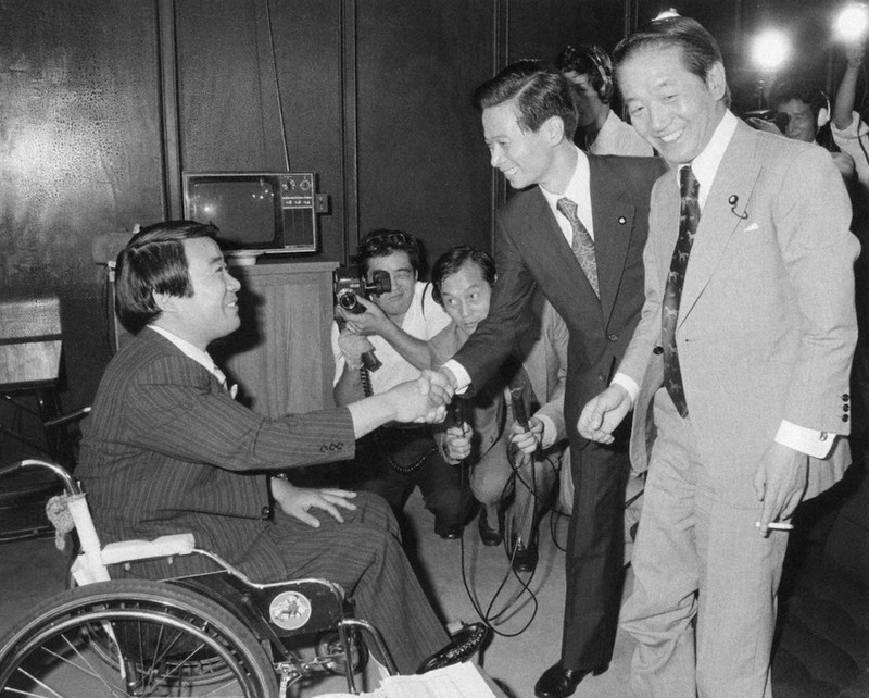 議員バッチを胸に笑顔で握手する左から八代英太、江田五月、高橋圭三の各新人議員=国会第19控室で