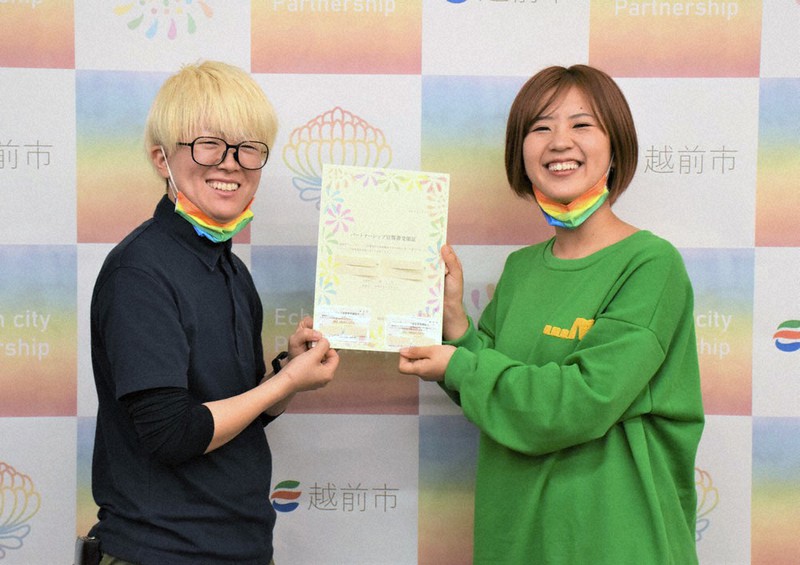 パートナーシップ宣誓書受領証を受け取り笑顔の竹内パンダさん(左)とパートナーの女性=福井県越前市で、国本ようこ撮影
