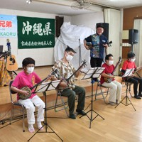 「波島三線クラブ」のメンバーと一緒に演奏する宮村さん（中央奥）と照屋さん（左端）