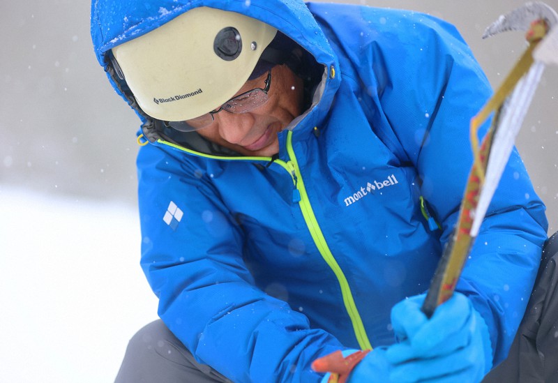 吹雪の中、内蔵助氷河でピッケルを手に雪渓に隠れる氷体を探す飯田肇さん=富山県・立山で2022年10月6日、滝川大貴撮影