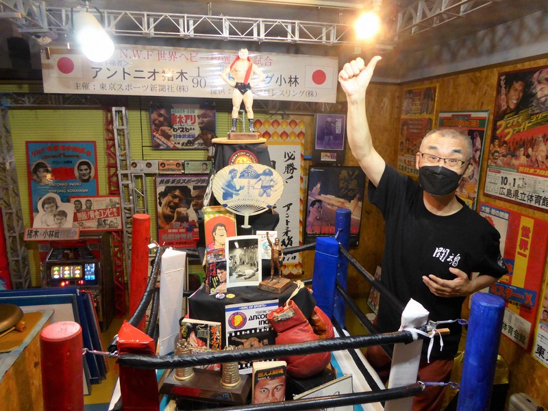 「猪木タワー」など貴重な品々が並ぶ美術館内で猪木さん得意のポーズを決める、館長の湯沢利彦さん=京都市左京区で2022年10月19日午後8時16分、千葉紀和撮影