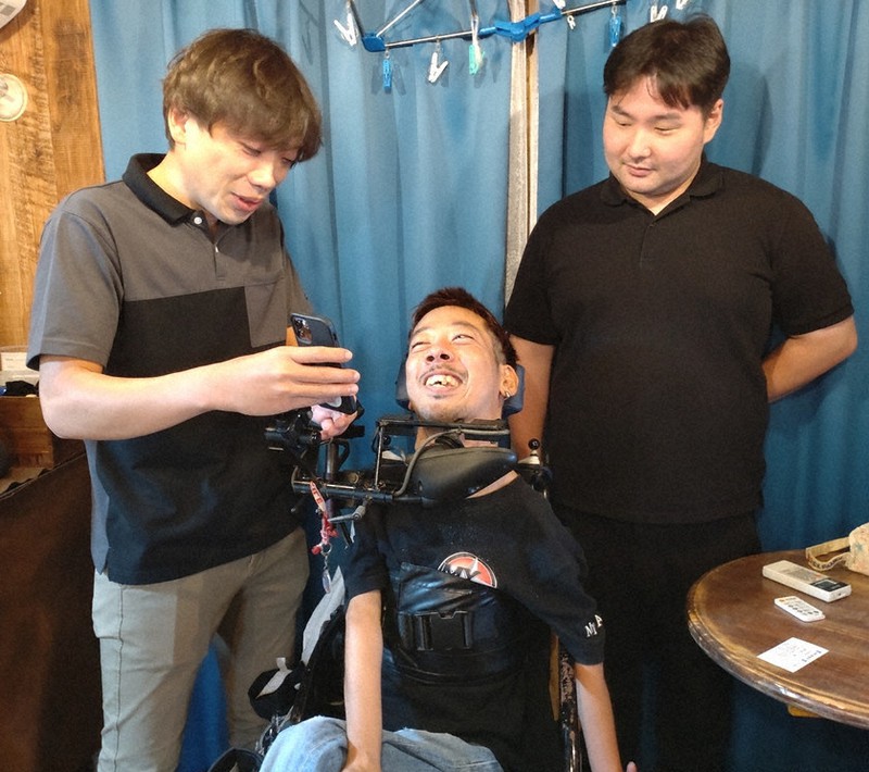 杉山健太郎さん(中央)と談笑する柴倉雄介さん(左)、介助者の香月一哉さん=八王子市内の杉山さん宅で