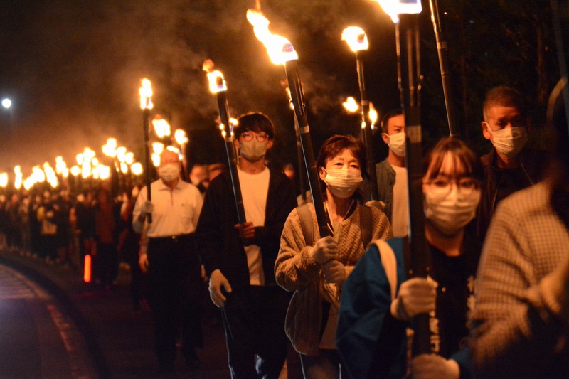たいまつを掲げ、高台まで歩く参加者ら=広川町で2022年10月22日午後5時59分、山口智撮影