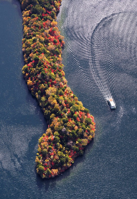 紅葉に染まった中禅寺湖の八丁出島付近を巡る遊覧船=栃木県日光市で2022年10月21日午後1時43分、本社ヘリから手塚耕一郎撮影