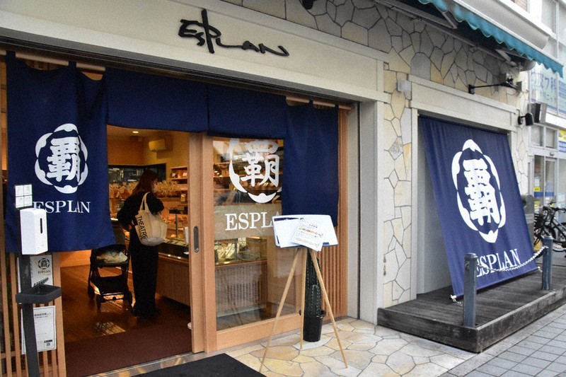 入り口に茶屋の頭文字である「覇」の字が書かれたのれんを掲げているパン屋「エスプラン」=横浜市鶴見区で2022年10月19日、池田直撮影