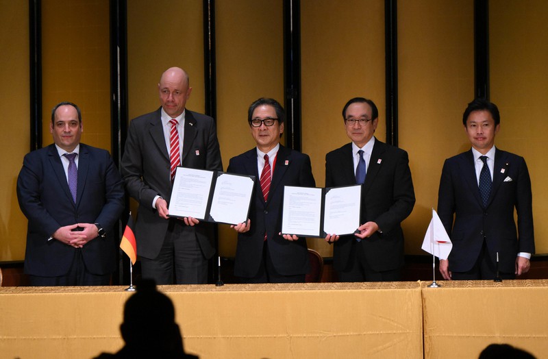 2025年大阪・関西万博の公式参加契約の調印式で記念撮影をする日本国際博覧会協会の石毛博行事務総長(中央)ら=大阪市北区で2022年10月25日午後6時49分、北村隆夫撮影