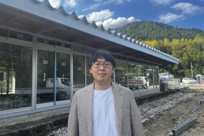 建設中の神山まるごと高専の新校舎の前に立つ事務局長の松坂孝紀さん＝徳島県神山町で2022年10月21日（同校提供）