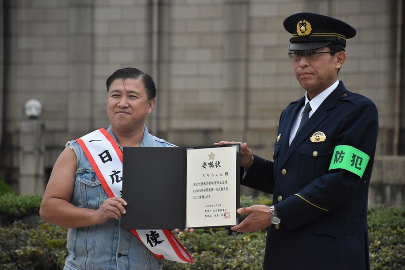 寺島明雄・四谷署長(右)から「一日広報大使」の委嘱状を受け取るスギちゃん=東京都新宿区霞ケ丘町の聖徳記念絵画館前で2022年11月1日午後2時16分、遠藤龍撮影
