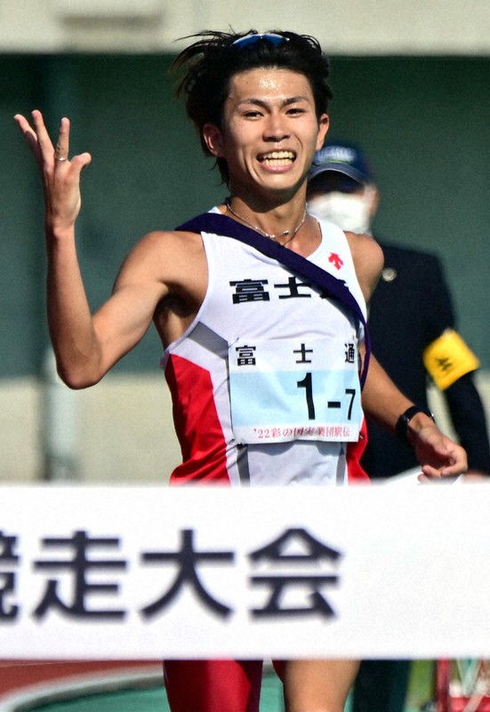 3連覇を示す3本指を立てて、1位でフィニッシュした富士通の飯田貴之=埼玉県熊谷市で2022年11月3日、北山夏帆撮影