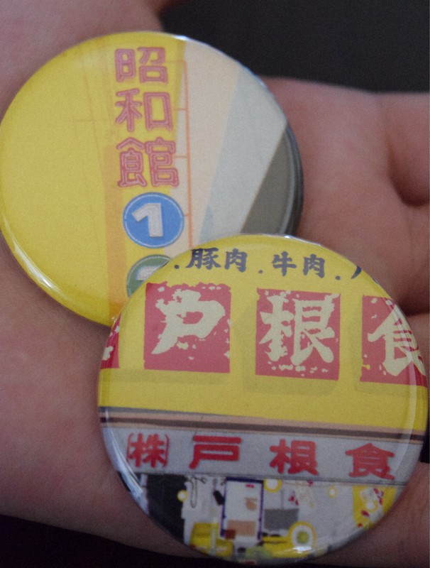 岡崎さんデザインの缶バッジには、火災で焼損した店の看板をモチーフにしたものもある=北九州小倉北区で2022年11月2日午後4時11分、青木絵美撮影