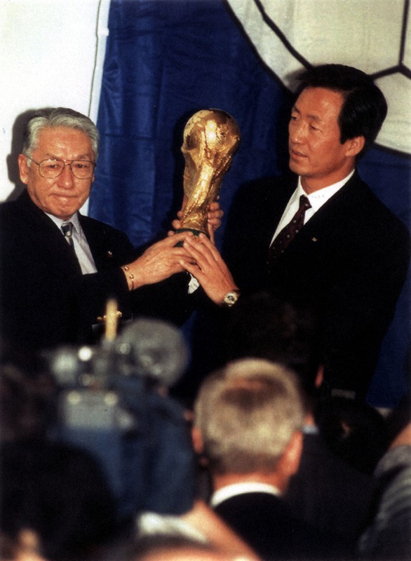 日韓共催の決定を受け、W杯を掲げる長沼健日本協会会長(左)と鄭夢準韓国協会会長=チューリヒで1996年5月、AP